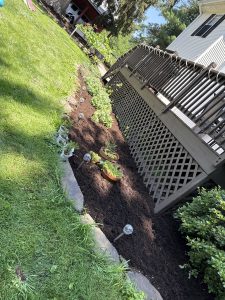 Mulched garden bed with plants along backyard deck by Justin's Lawn Service